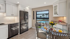 Una cucina moderna con elettrodomestici in acciaio inossidabile, un'area pranzo con tavolo in vetro e vista su una piscina.