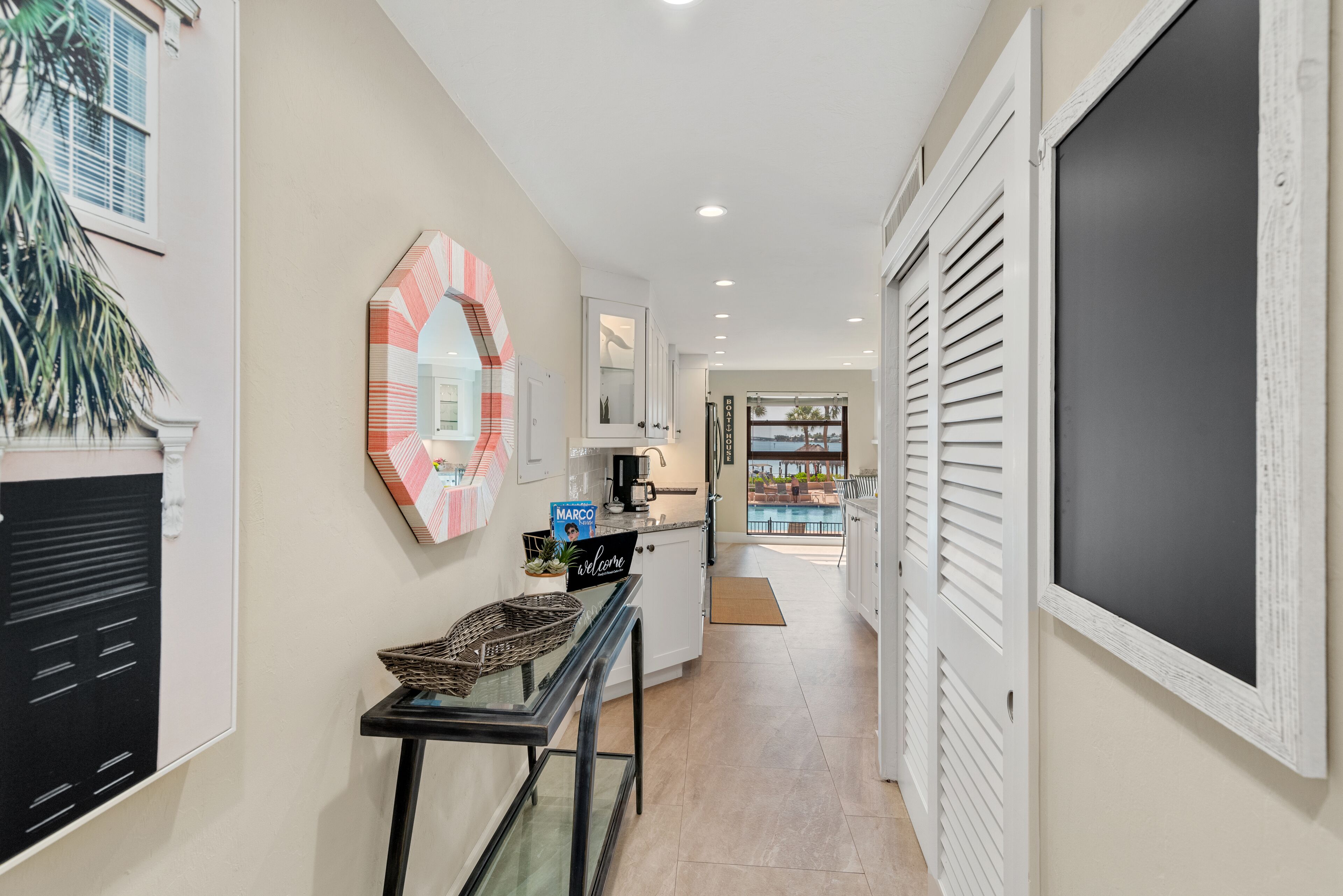A hallway with a console table, a decorative mirror, and a view of a pool area.