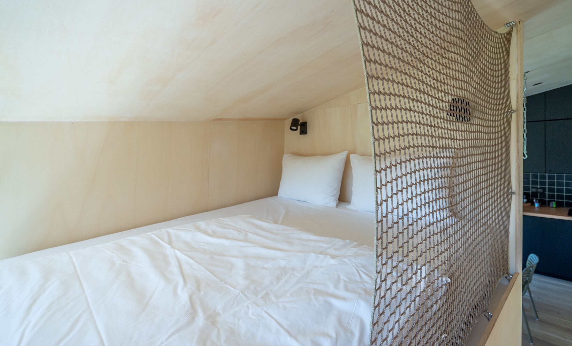 A single bed with white bedding in a room with wooden walls and a slanted ceiling.