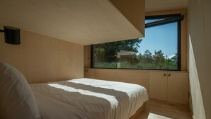 A bedroom with a bed, wooden walls, a window, and a ceiling light. - ICI - Tiny house 40 m2 for 4 people (Arette)