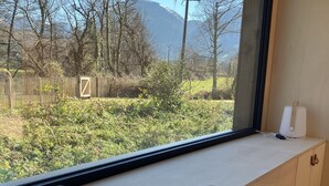 A room with a large window, a wooden cabinet, and a towel on the windowsill. - ICI - Tiny house 40 m2 for 4 people (Arette)