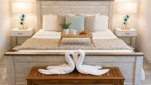 Una camera da letto ordinata con un letto, comodini, un vassoio per la colazione e una panca di legno con asciugamani.