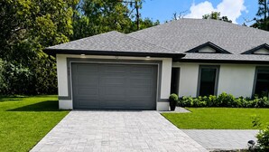 Una casa moderna con garage, vialetto lastricato e prato curato.