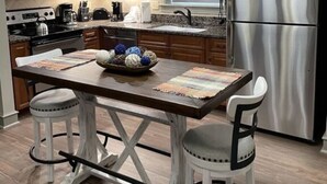A modern kitchen with wooden cabinets, stainless steel appliances, and a central island with stools.
