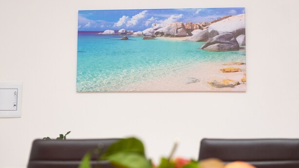 Een strand met helder turquoise water en grote rotsen.