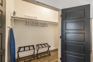 A room with a dark door, a white wall, a towel rack with hangers, and a bench. - Brand new 4 BR, 4Bath Townhome with amazing rooftop! (Nashville)