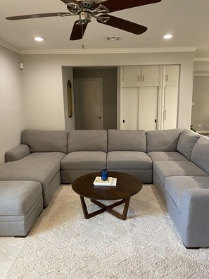 Relax in this stylish living room with a comfortable sofa, coffee table, and ceiling fan.