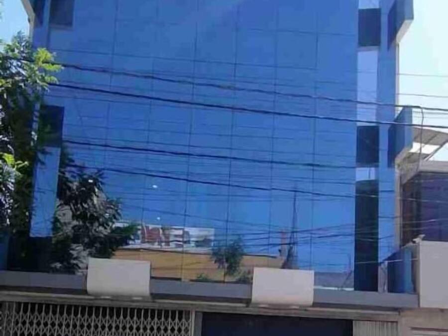 Un edificio con fachada azul y entrada protegida por una reja.