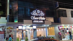A hotel named "Grand Hotel" with a neon sign, a visible entrance, and various shops on the ground floor. - San Isidro Grand Hotel (Nazca)