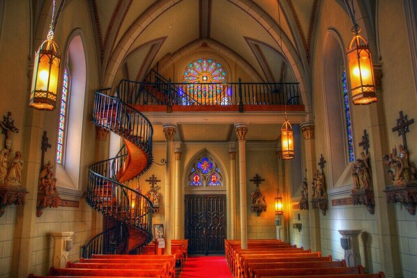 Stunning Gothic architecture features a central spiral staircase and stained glass windows.