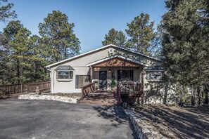 A single-story house with a front porch, a stone retaining wall, and a wooden deck.