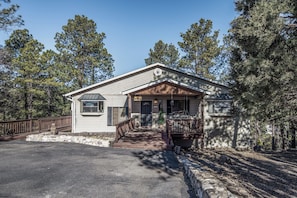 A single-story house with a front porch, a stone foundation, and a wooden deck. - Journeys End by Ruidoso Vacation Rentals (Ruidoso)