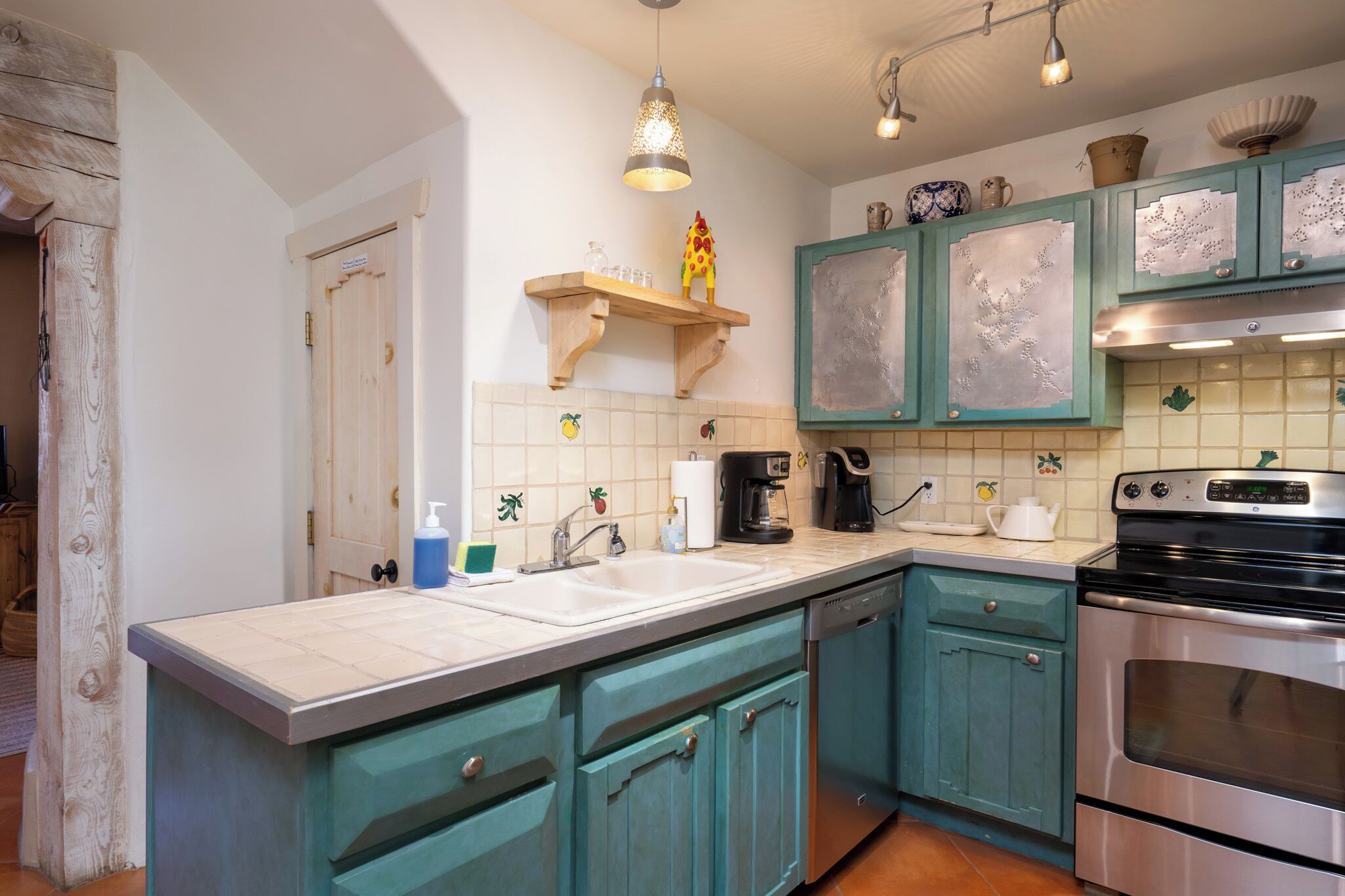 A kitchen with teal cabinets, a double sink, and a stainless steel oven.