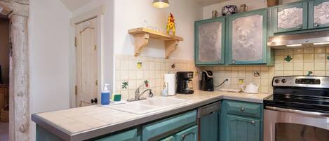 A kitchen with teal cabinets, a double sink, and a stainless steel oven.