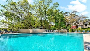 A clear blue pool with lounge chairs and trees in the background. - Saint Andrews Common 1774 by Hilton Head Retreats (Hilton Head Island)