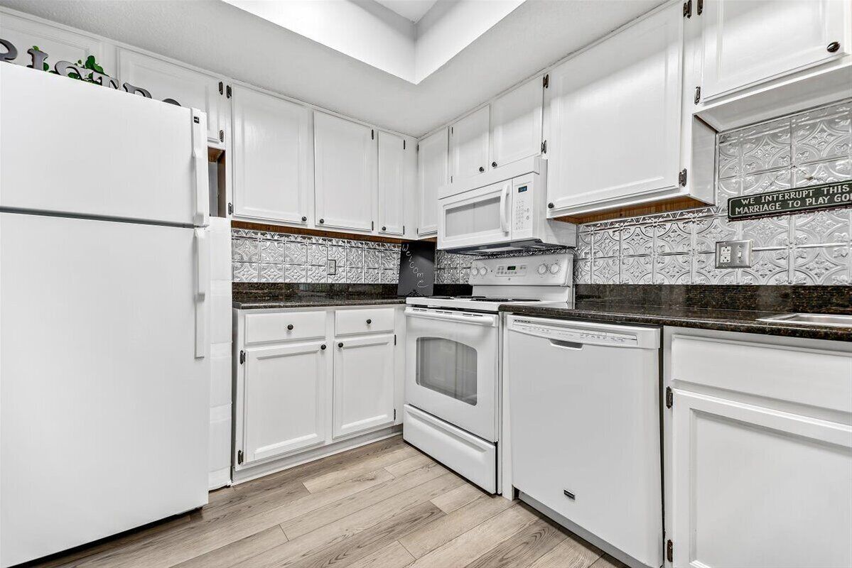 A kitchen with white cabinets, a microwave, an oven, and a dishwasher.