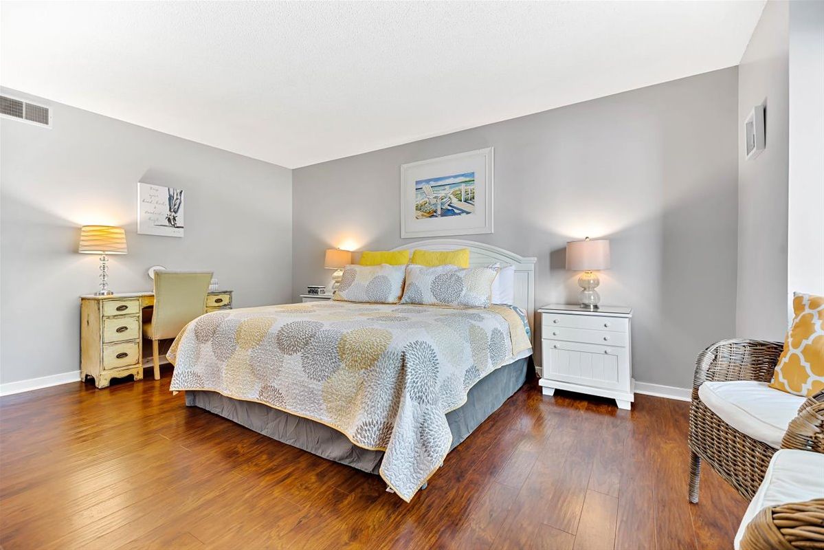 A bedroom with a bed, bedside tables, a chair, and artwork on the walls.