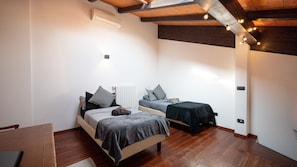A bedroom with two beds, wooden flooring, and a ceiling with exposed beams.