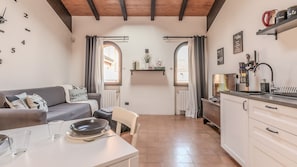 A compact living space with a dining area, kitchenette, and a sofa with a view to the outside.