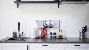 Een keuken met een modern ontwerp, met een spoelbak, waterkoker, koffiezetapparaat en diverse keukengerei.