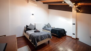 Een slaapkamer met twee bedden, houten vloeren, een dakraam en een kleine tafel.