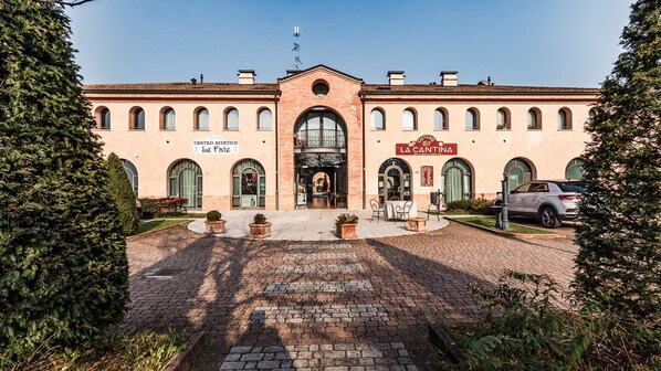 A building with a central entrance, arched windows, and signage for 'CENTRO ESTETICO Le Fate' and 'LA CANTINA.'