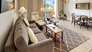 A modern living room with a sofa, two armchairs, a coffee table, and a dining area with chairs and a table.