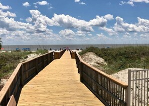 A wooden boardwalk leading to a beach with a clear sky and clouds. - Fiddler's Cove 7L by Hilton Head Retreats (Hilton Head Island)