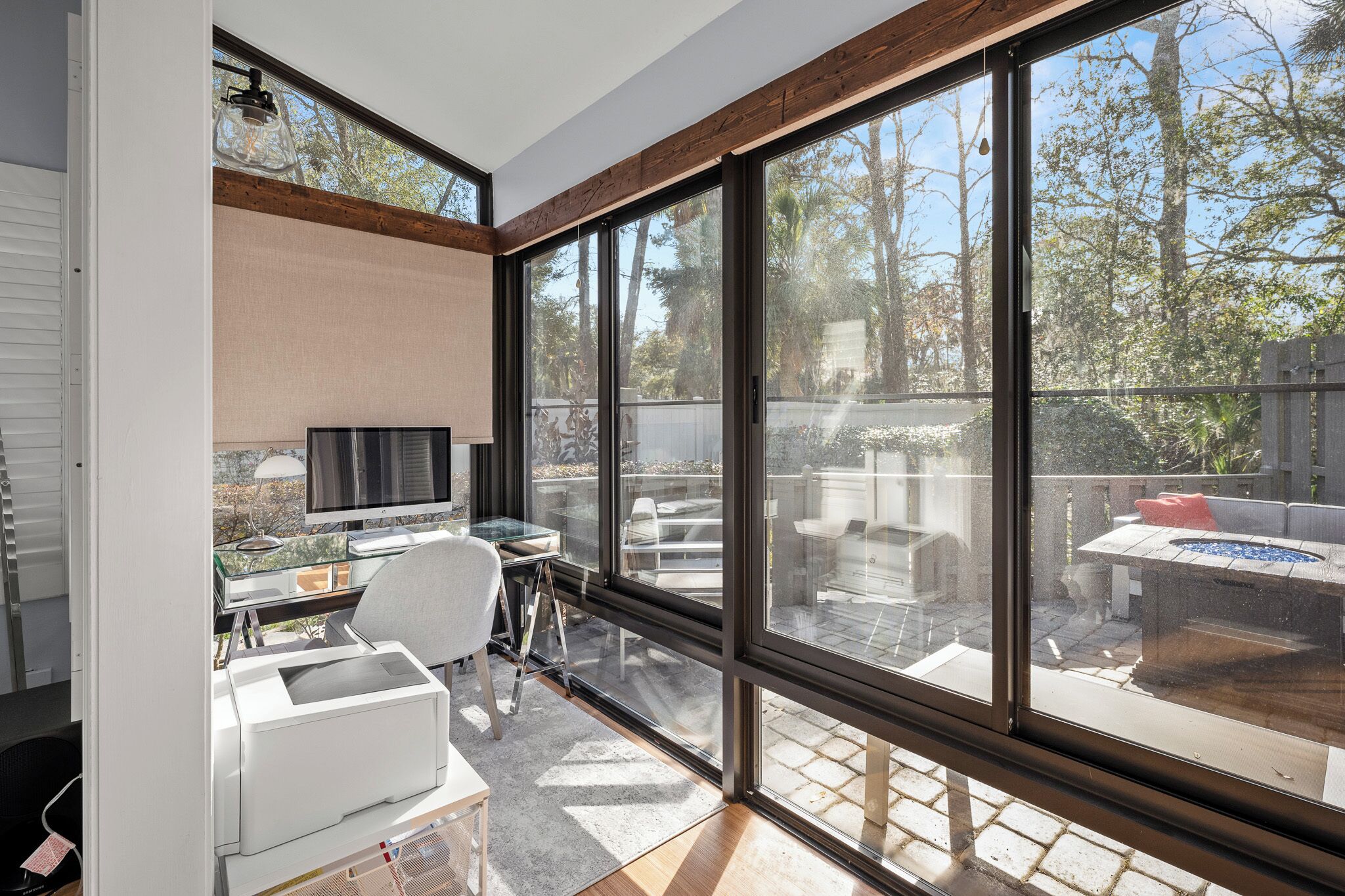 A modern room with large windows, a desk, a chair, and a television.