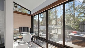 A modern room with large windows, a desk, a chair, and a television. - Loggerhead Lodge by Distinctive Beach Rentals (Ponte Vedra Beach)