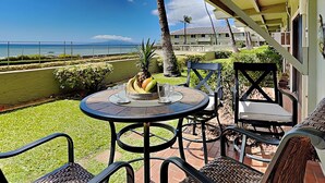 Un patio con una mesa para dos, un frutero y vistas al océano.