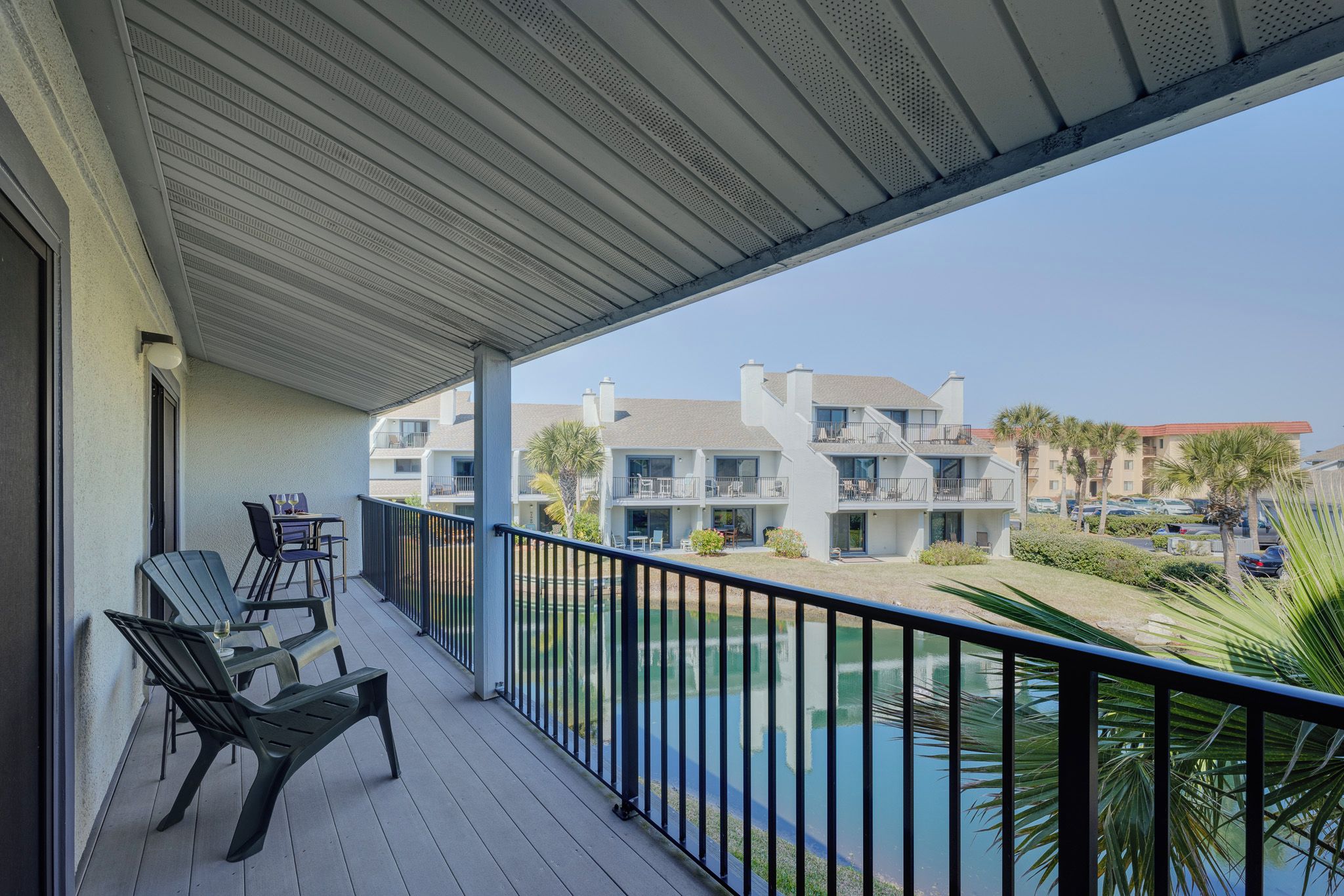 A balcony with outdoor furniture, a pool, and a view of multi-story buildings.