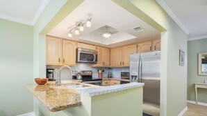 A kitchen with granite countertops, stainless steel appliances, and wooden cabinets. - Sea Winds 51 by Distinctive Beach Rentals (St. Augustine)