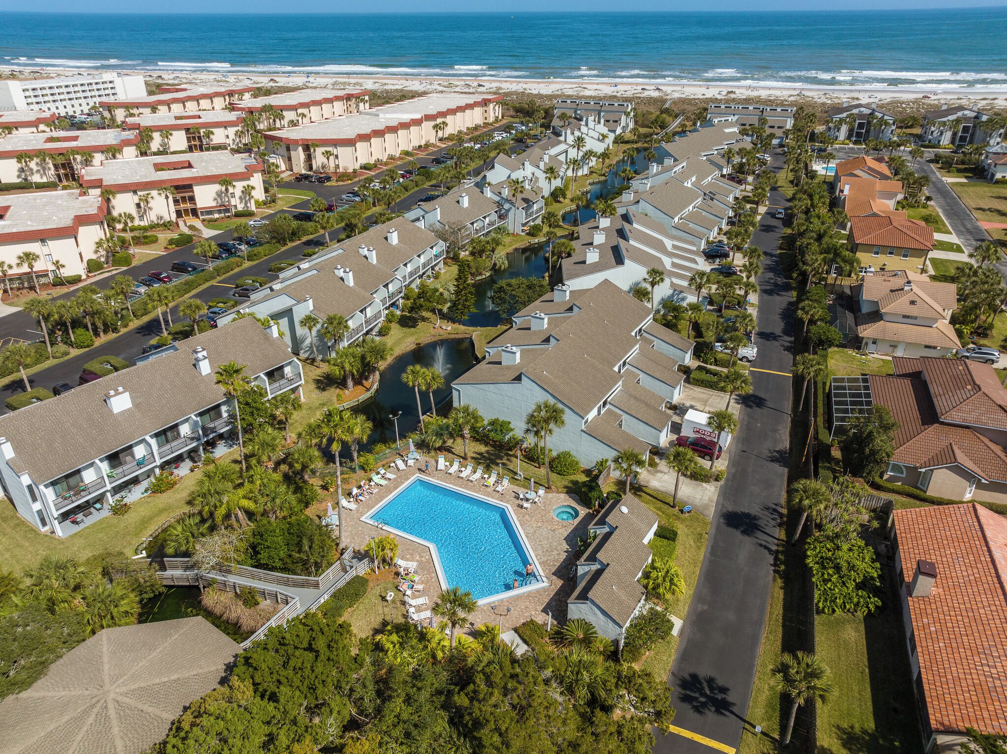 A resort with a swimming pool, beachfront view, and multiple buildings.