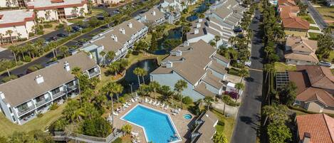 A resort with a swimming pool, beachfront view, and multiple buildings.