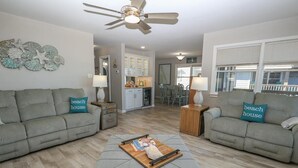 A living room with two grey sofas, a wooden coffee table, and a ceiling fan. - 🏖️ Someplace Else - Oceanfront 4 BR Townhome w/Gorgeous Sunrise Views 🌅 (Southern Shores)