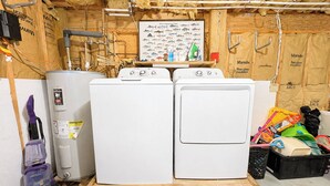 A utility room with two stacked washing machines, a water heater, and various tools and supplies. - Capt'n Rons - 🏖️ 4BR Southern Shores Oceanside home w/Private Pool 🏖️ (Southern Shores)