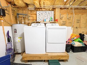 A utility room with two stacked washing machines, a water heater, and various tools and supplies. - Capt'n Rons - 🏖️ 4BR Southern Shores Oceanside home w/Private Pool 🏖️ (Southern Shores)