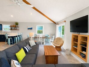 A modern living room with a sofa, coffee table, and a dining area with chairs and a table.