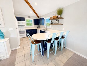 A kitchen with a central island, blue chairs, and a white countertop.