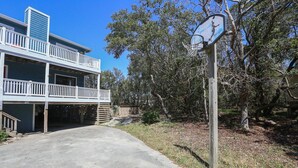 A two-story building with a balcony and a basketball hoop. - Capt'n Rons - 🏖️ 4BR Southern Shores Oceanside home w/Private Pool 🏖️ (Southern Shores)
