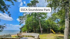A wooden deck with benches, a playground with a slide, and a view of the sea. - Capt'n Rons - 🏖️ 4BR Southern Shores Oceanside home w/Private Pool 🏖️ (Southern Shores)