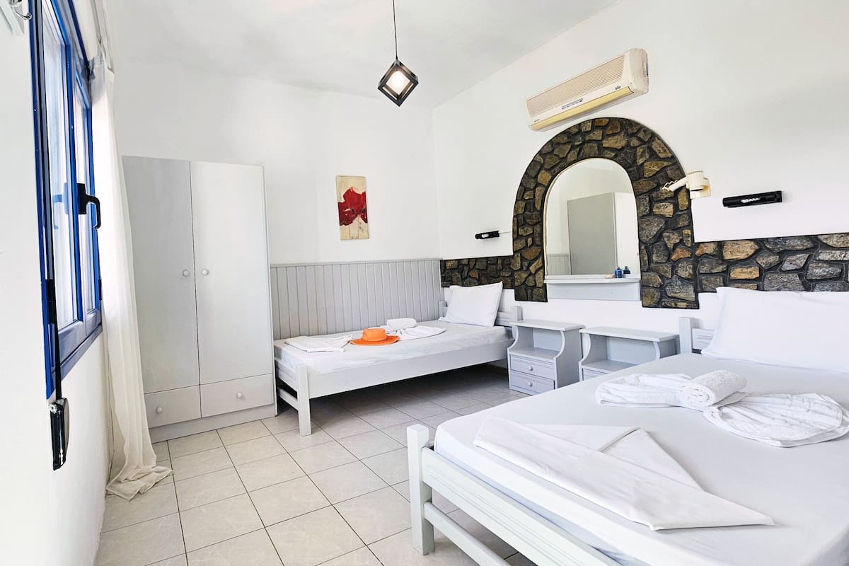 Une chambre d’hôtel avec un lit, un petit lit, une armoire, un miroir et un mur en pierre.