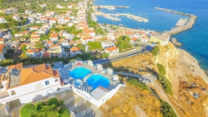 A coastal town with a prominent swimming pool, marina, and houses with red-tiled roofs. - Pavlis Studios Ormos (Samos)