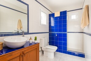 A bathroom with a large white sink, a toilet, and blue-tiled walls.