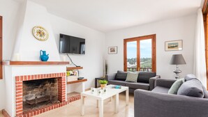 Ein Wohnzimmer mit Kamin, einer Couch, einem Fernseher und einem Fenster mit Aussicht.