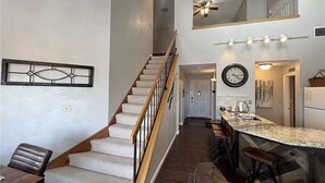 A spacious living area with a staircase, a kitchen with a large island, and a dining area with a couch and chairs. - Summer Getaway: Hiking, Swimming, Fishing, Biking, Golfing, Ski In/Out + more (Hidden Valley)