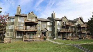 A multi-story residential building with balconies, a front porch, and a grassy yard. - Summer Getaway: Hiking, Swimming, Fishing, Biking, Golfing, Ski In/Out + more (Hidden Valley)