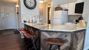 A kitchen with a herringbone-patterned backsplash, a central island with stools, and a refrigerator. - Summer Getaway: Hiking, Swimming, Fishing, Biking, Golfing, Ski In/Out + more (Hidden Valley)