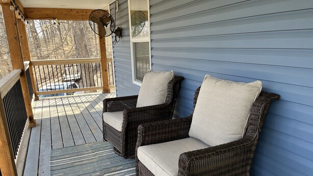 A porch with two wicker chairs, a wooden railing, and a patterned rug. - Lake Daze, Blue Cottage <1mile to Jamestown Marina with space to trailer boat. (Jamestown)